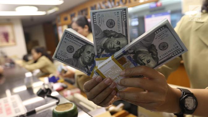 Pekerja menunjukan Dolar AS di jasa penukaran uang asing di Jakarta, Rabu (19/6/2019). Nilai tukar rupiah terhadap Dolar AS sore ini Rabu (19/6) ditutup menguat sebesar Rp 14.269 per dolar AS atau menguat 56,0 poin (0,39 persen) dari penutupan sebelumnya. (Liputan6.com/Angga Yuniar)