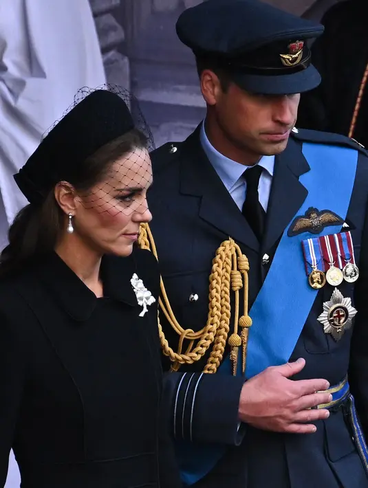 Kate Middleton bersama Pangeran William berjalan mengikuti prosesi persemayaman Ratu Elizabeth II di Westminster Hall di London (14/9/2022). Bros yang dikenakan Kate ini dulu dimiliki oleh Ratu Elizabeth II, sebelum diberikan kepada istri Pangeran William tersebut.  Dalam situs The Court Jeweller, sang ratu pernah menggunakan bros tersebut dalam kunjungan ke Seoul, Korea Selatan pada 1999. (AFP/Ben Stansall)