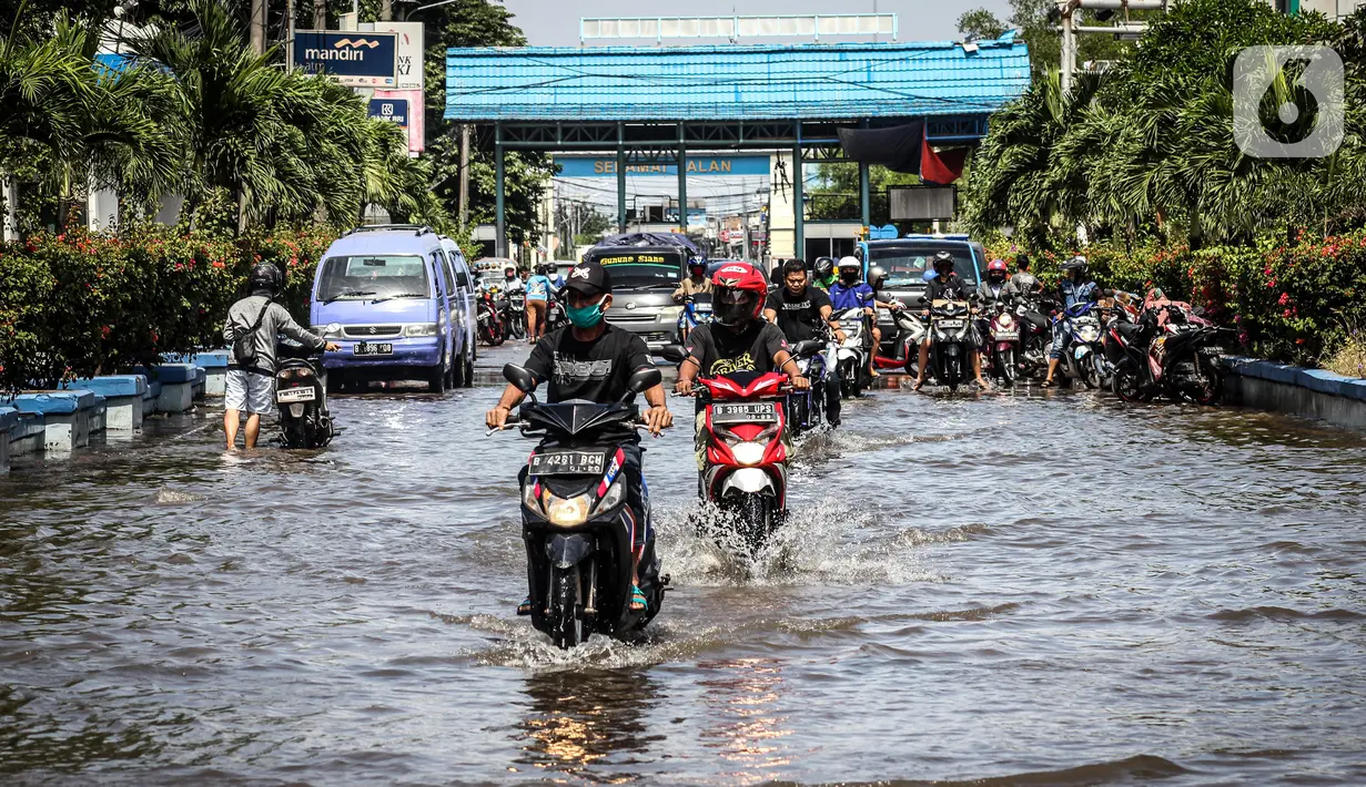Kendaraan bermotor melintasi jalan yang tergenang air rob (banjir pasang air laut) di Kawasan Pasar Ikan Muara Baru, Jakarta, Kamis (4/6/2020). Banjir rob di Pelabuhan Muara Baru tersebut terjadi akibat cuaca ekstrem serta pasangnya air laut. (Liputan6.com/Faizal Fanani)