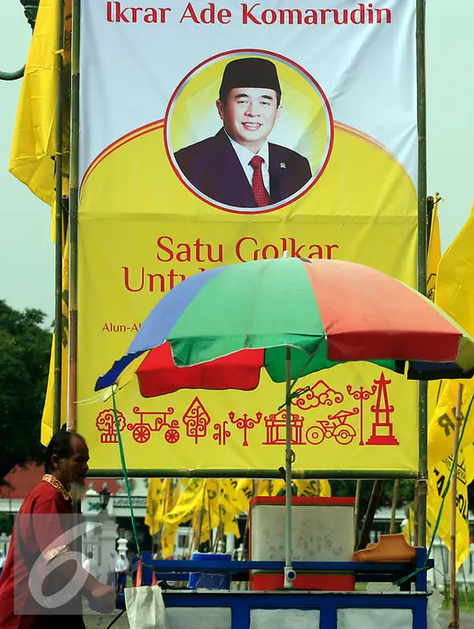 Seorang PKL melintasi baliho Ade Komarudin di kawasan alun alun utara Yogyakarta, Jumat (11/3/2016). Ade Komarudin akan mendekalrasikan pencalonan ketua Umum DPP Golkar yang akan bertarung pada Munaslub 2016. (Liputan6.com/Boy Harjanto)