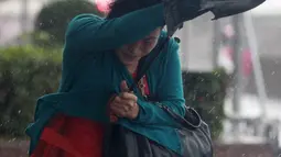 Warga berlindung di balik payung untuk menghindari angin kencang yang disebabkan topan Dujuan di Taipei, Taiwan, Senin (28/9). Ribuan orang diungsikan untuk menghadapi topan raksasa Dujuan yang diprediksikan akan menyerang Taiwan. (REUTERS/Pichi Chuang)