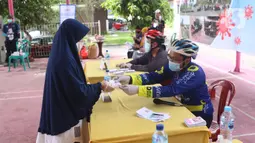 Petugas memberikan surat suara kepada warga yang akan menggunakan hak pilihnya dalam Pilkada 2020 di TPS 23 Pondok Jagung Timur, Tangerang Selatan, Rabu (9/12/2020). TPS Pilkada Tangsel itu menggunakan tema hobi dimana petugasnya mengenakan pakaian untuk bersepeda. (Liputan6.com/Angga Yuniar)