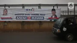 Pengedara melintas di depan alat peraga kampanye (APK) yang terpasang di kawasan Depok, Jawa Barat dan Ciputat, Tangerang Selatan, Minggu (18/10/2020). KPU Kota Tangsel dan Depok membagikan sejumlah alat peraga kampanye kepada pasangan calon Pilkada 2020 serentak. (Liputan6.com/Johan Tallo)