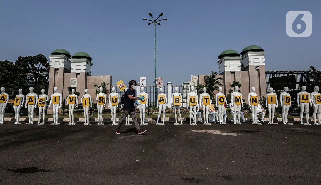 Aktivis Greenpeace Indonesia melintasi puluhan maneken saat menggelar aksi damai di depan gerbang kompleks DPR, Jakarta Pusat, Senin (29/6/2020). Aksi tersebut dilakukan sebagai bentuk penolakan terhadap RUU Omnibus Law. (Liputan6.com/Johan Tallo)
