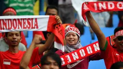 Suporter Timna Indonesia U-22 bersorak membentangkan syal sebelum pertandingan melawan Thailand selama Asian Games ke-29 (SEA Games) di Stadion Shah Alam, Kuala Lumpur, Malaysia (15/8). (AFP Photo/Manan Vatsyayana)