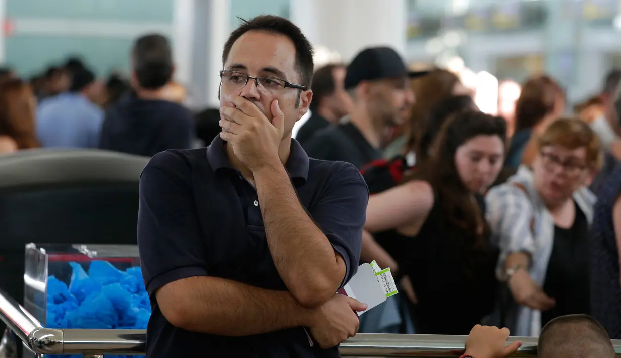 Ekspresi penumpang saat menunggu di pintu area kontrol bandara Terminal 1 Barcelona-El Prat di Barcelona, Spanyol (4/8). Pekerja juga mengeluh stres dengan ketentuan pihak perusahaan yang mengeluarkan peraturan 16 jam kerja. (AP Photo/Manu Fernandez)