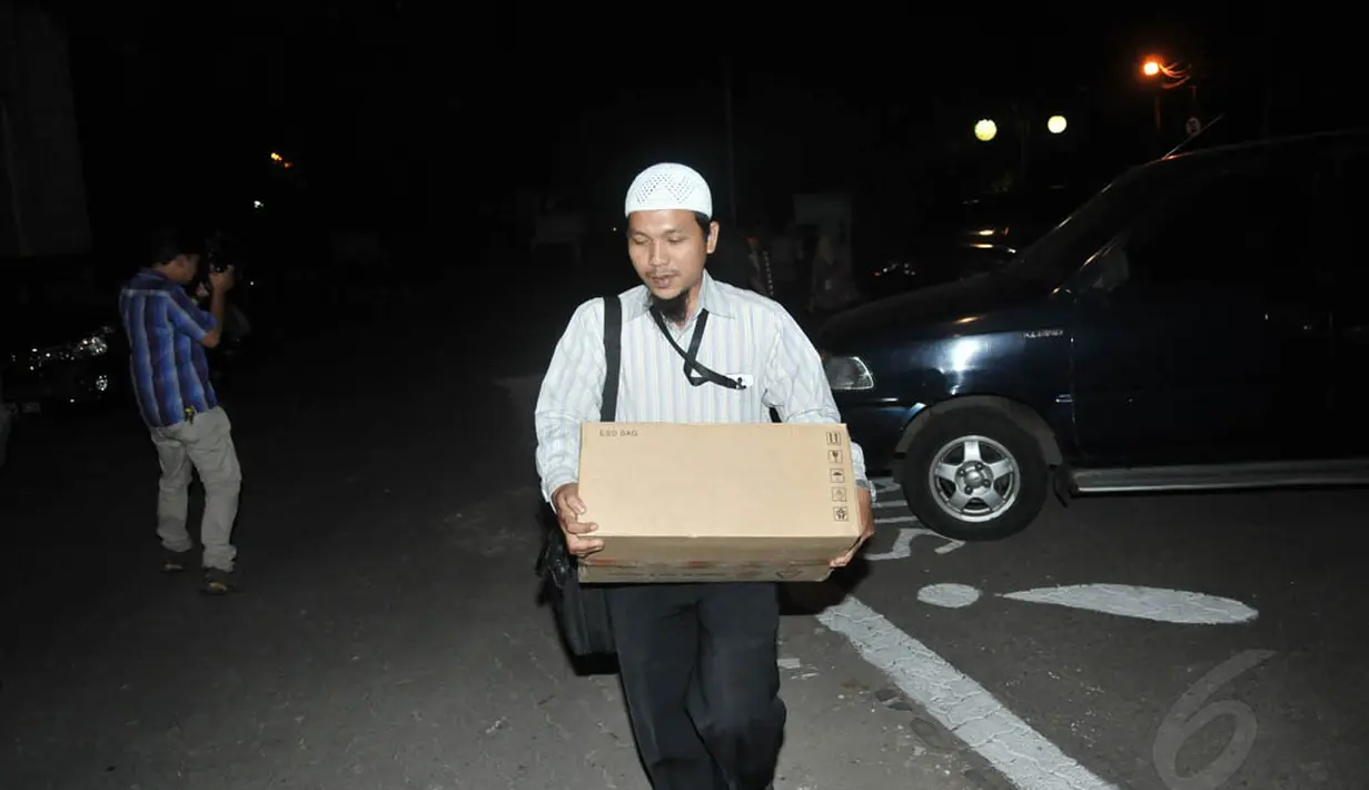 Dengan membawa sebuah kardus, seorang penyidik keluar meninggalkan gedung Kemenag, Jakarta, Kamis (22/5/14). (Liputan6.com/Johan Tallo)