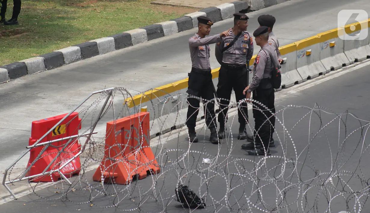Personel Kepolisian berjaga dibalik barikade kawat berduri yang menutup ruas Jalan Medan Merdeka Barat, Jakarta, Senin (28/10/2019). Penutupan ini antisipasi aksi unjuk rasa mahasiswa mendesak Presiden Jokowi segera mengeluarkan Perppu KPK. (Liputan6.com/Helmi Fithriansyah)