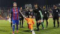 Striker Barcelona Lionel Messi menggandeng bocah asal Afghanistan Murtaza Ahmadi jelang dimulainya laga melawan Al Ahli di Doha, Selasa (13/12/2016). (AFP/Karim Jaafar)