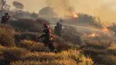 Kebakaran hutan yang terjadi pada sore hari, dipicu oleh gelombang panas dan angin kencang yang menghambat upaya pemadaman. (Costas Metaxakis/AFP)