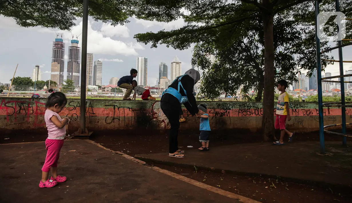 Sejumlah anak bermain di taman bermain yang terdapat di Bantaran Banjir Kanal Barat Kawasan Petamburan, Jakarta, Minggu (12/12/2021). Minimnya taman bermain di pemukiman padat penduduk membuat anak-anak seringkali bermain di tempat yang tidak semestinya. (Liputan6.com/Faizal Fanani)