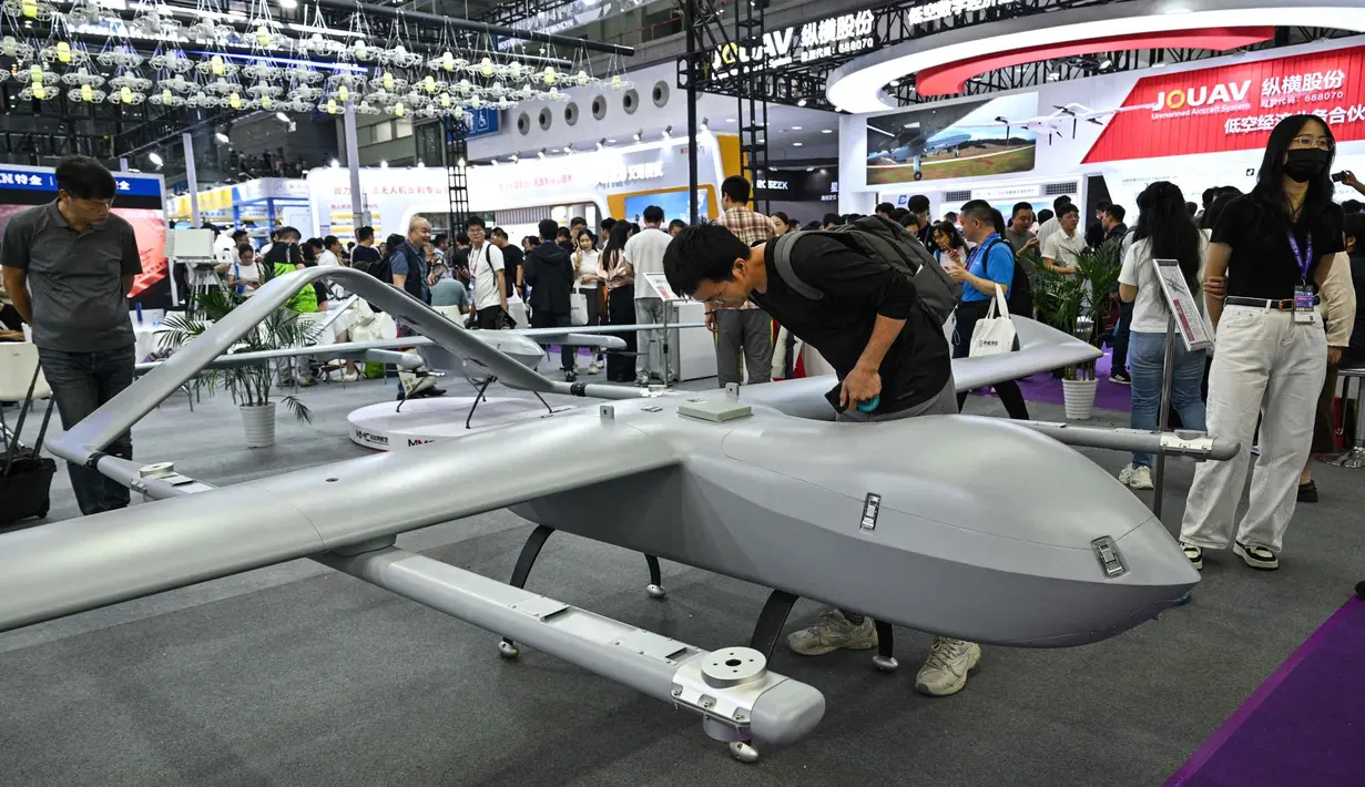 Seorang pria melihat model drone VTOL sayap tetap M12 di stan Micro Multi Copter (MMC) selama Drone World Congress (DWC) di Shenzhen pada 21 Mei 2026. (HECTOR RETAMAL/AFP)