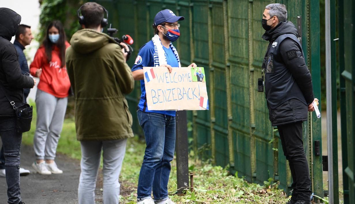 Fans sambil membawa poster menunggu kedatangan Karim Benzema di Pusat latihan Timnas Prancis di Clairefontaine-en-Yvelines, Rabu (26/5/2021). Benzema kembali memperkuat Timnas Prancis setelah enam tahun absen. (AFP/Franck FIfe)