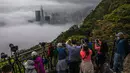 Orang-orang mengambil foto kabut di atas Hong Kong, Selasa (22/3/2022). Kabut tebal menyelimuti Hong Kong pada musim semi ketika wilayah tersebut dipengaruhi oleh udara dingin dan hangat bergantian. (AFP/Dale De La Rey)