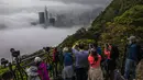 Orang-orang mengambil foto kabut di atas Hong Kong, Selasa (22/3/2022). Kabut tebal menyelimuti Hong Kong pada musim semi ketika wilayah tersebut dipengaruhi oleh udara dingin dan hangat bergantian. (AFP/Dale De La Rey)