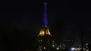 Menara Eiffel menyala dengan warna biru dan kuning, warna bendera Ukraina di Paris (25/2/2022). Pasukan Rusia menyerang ibu kota Ukraina pada Jumat (25/2) dengan tembakan dan ledakan dalam invasi ke negara demokratis yang memicu kekhawatiran perang yang lebih luas di Eropa. (AFP/ Thomas Coex)