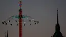 Pengunjung menaiki wahana ayunan ontang-anting di depan gereja St. Paul saat festival bir Oktoberfest di Munich, 27 September 2018. Festival yang merupakan salah satu acara paling terkenal di Jerman ini sudah ada sejak tahun 1800an. (AP/Matthias Schrader)