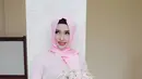 Calon istri Gubernur Kalteng Sugianto Sabran, Yulistra Ivo mengenakan busana berwarna pink bepose sambil memegang bunga. (instagram/yuliastraivo)