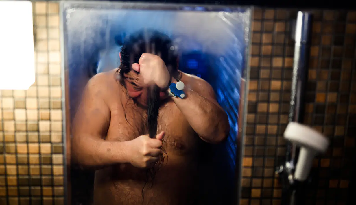 You Sasaki membilas dirinya di pemandian air panas Jepang atau onsen di Yokohama, prefektur Kanagawa pada 29 Mei 2020. Dengan pencabutan status darurat nasional secara resmi pada Senin (25/5) lalu, banyak bisnis yang mulai beroperasi kembali tak terkecuali dengan onsen. (Behrouz MEHRI/AFP)