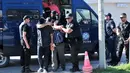 Polisi mengawal dua dari 8 perwira militer pendukung kudeta Turki, di kota Alexandroupoli, Minggu (17/7). 8 pria yang terbang dengan helikopter militer Turki itu ditahan petugas keamanan Yunani karena masuk secara ilegal. (Sakis MITROLIDIS/AFP)