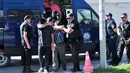 Polisi mengawal dua dari 8 perwira militer pendukung kudeta Turki, di kota Alexandroupoli, Minggu (17/7). 8 pria yang terbang dengan helikopter militer Turki itu ditahan petugas keamanan Yunani karena masuk secara ilegal. (Sakis MITROLIDIS/AFP)