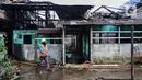 Petugas pemadam kebakaran melintas di depan salah satu rumah warga yang terbakar di Jalan Masjid Alhuda atau depan Stasiun Kebayoran Lama RT 05/01, Jakarta Selatan, Selasa (24/5/2022). Petugas pun mengerahkan 27 unit mobil pemadam kebakaran dari Sudin Damkar Jakarta Selatan ke lokasi kejadian. (Liputan6.com/Johan Tallo)
