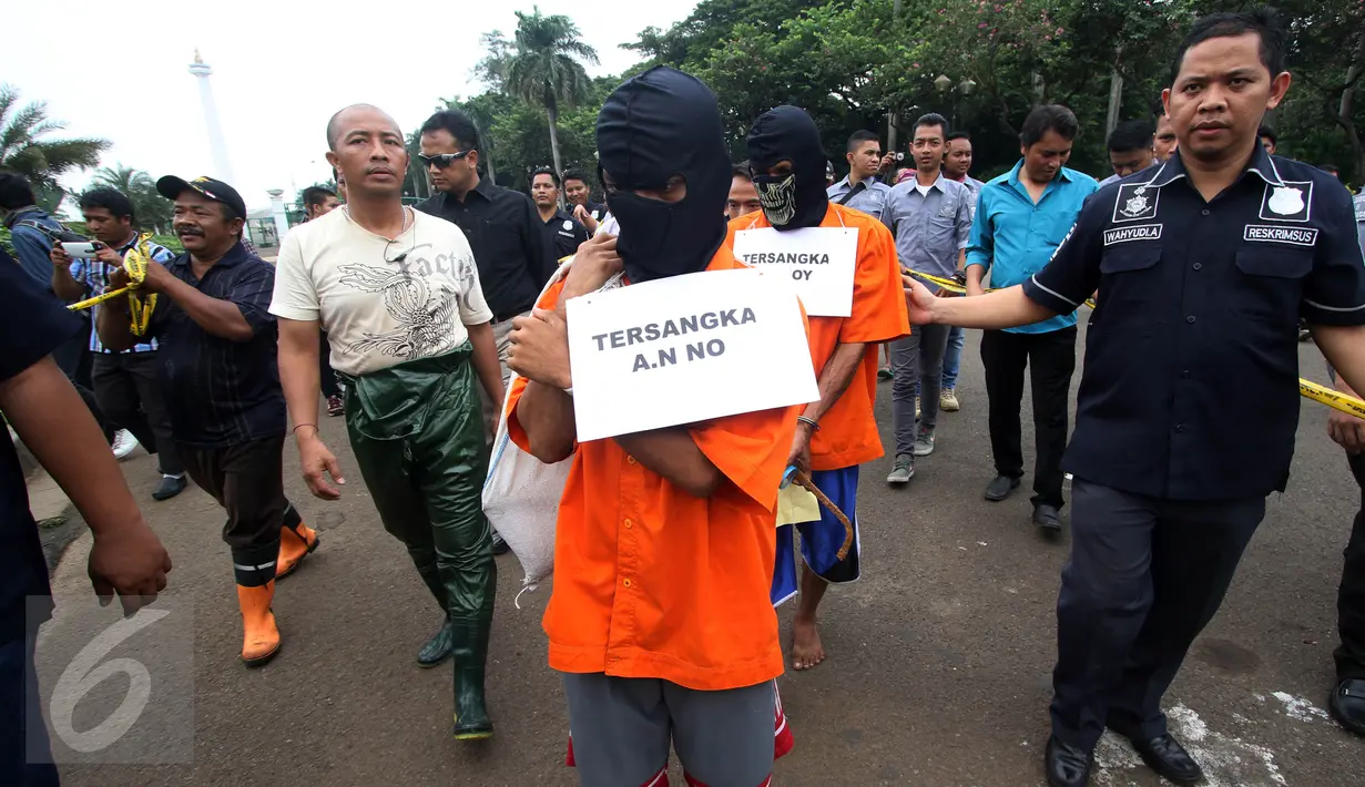 Polisi menggelar rekonstruksi kasus pencurian kabel di gorong-gorong di Jalan Medan Merdeka Selatan, Jakarta, Selasa (15/3). Empat dari enam tersangka dihadirkan untuk menunjukkan cara mereka memotong dan mencuri kabel. (Liputan6.com/Immanuel Antonius)
