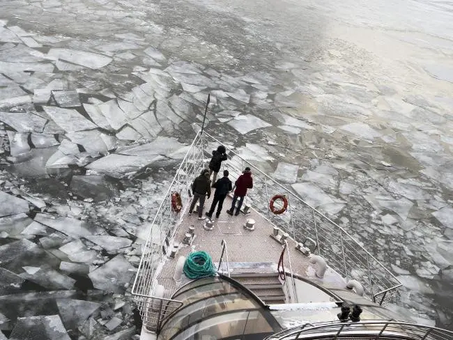 Penumpang berdiri di atas dek sebuah kapal pesiar yang didesain untuk menyusuri perairan di musim dingin, saat menembus Sungai Moskva yang beku di Moskow, Rusia. Senin, 26 Februari 2018. (Alexander Zemlianichenko / AP)