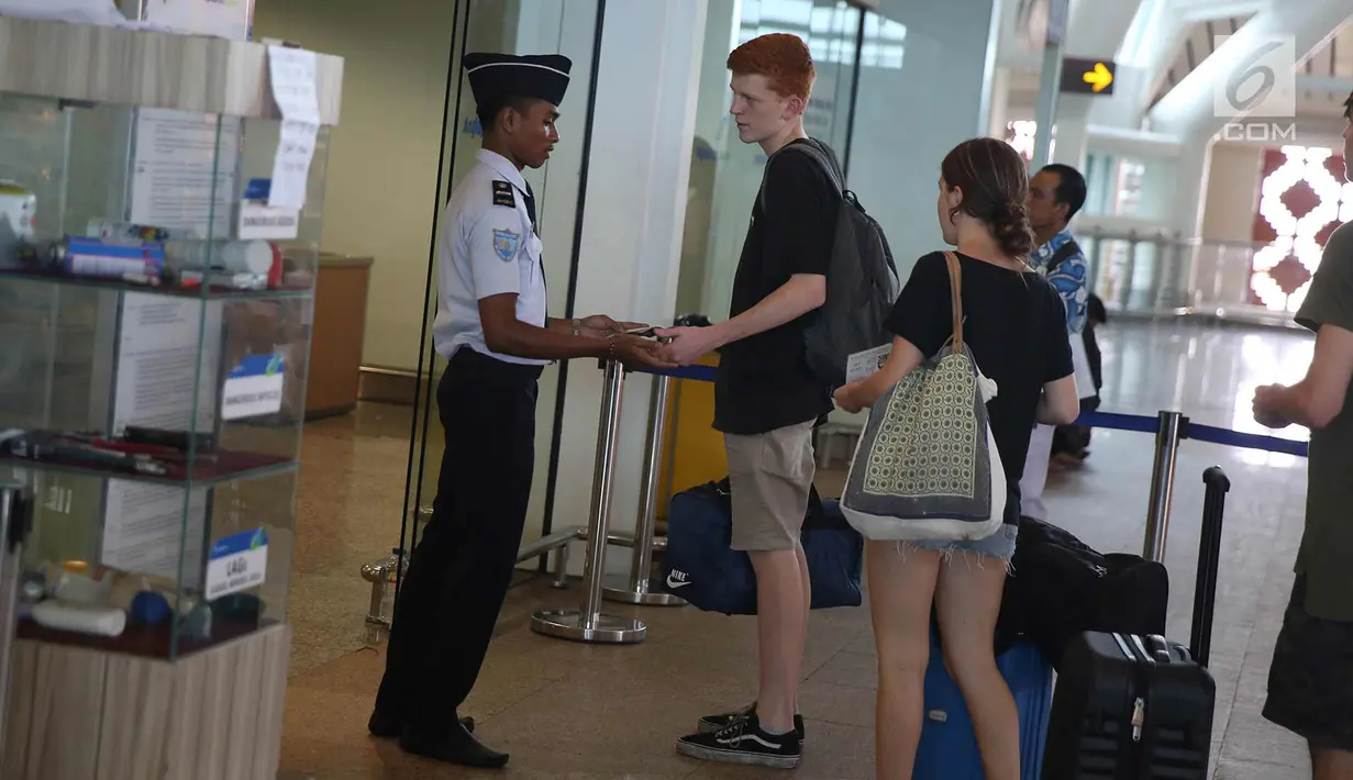 Petugas mengecek calon penumpang di Bandara Internasional I Gusti Ngurah Rai, Bali, Kamis (30/11). Sebanyak 55 penerbangan baik domestik dan internasional untuk kedatangan dan keberangkatan sudah beroperasi dengan normal. (Liputan6.com/Immanuel Antonius)