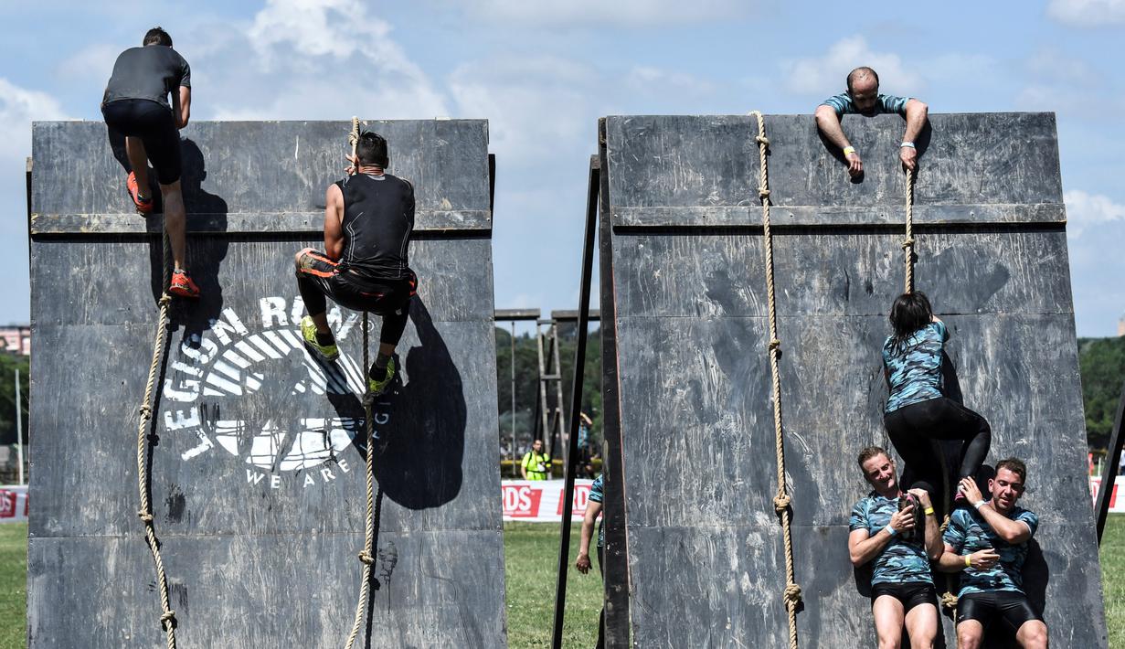 Peserta lomba memanjat tembok saat mengikuti "Legion Run" di Roma, Italia, Sabtu (13/4). Peserta harus melewati rintangan seperti dari lumpur, es dan kawat berduri dengan jarak tempuh 5 kilometer. (AFP PHOTO / Andreas SOLARO)