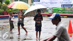 Bocah pengojek payung menunggu calon konsumen di tengah guyuran hujan, Jakarta, Selasa (1/11). Mereka mengenakan biaya jasa sewa payung mulai dari Rp.2000 hingga Rp.5000. (Liputan6.com/Angga Yuniar)
