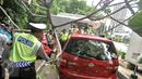 Petugas dibantu warga memindahkan pohon tumbang yang menimpa mobil saat terparkir di sebelah Pos Polisi Bundaran HI, Jakarta, Selasa (15/12). Tak ada korban jiwa akibat tumbangnya pohon yang disebabkan angin kencang tersebut. (Liputan6.com/Faizal Fanani)