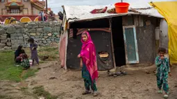 Gadis Kashmir Bakarwal menyaksikan berdiri di luar kamp sementara di pinggiran Srinagar, India, 31 Agustus 2020. Suku Bakarwals adalah kaum penggembala nomaden di Jammu Kashmir, yang berpindah-pindah untuk mencari padang rumput yang baik untuk ternak mereka. (AP Photo/Dar Yasin)