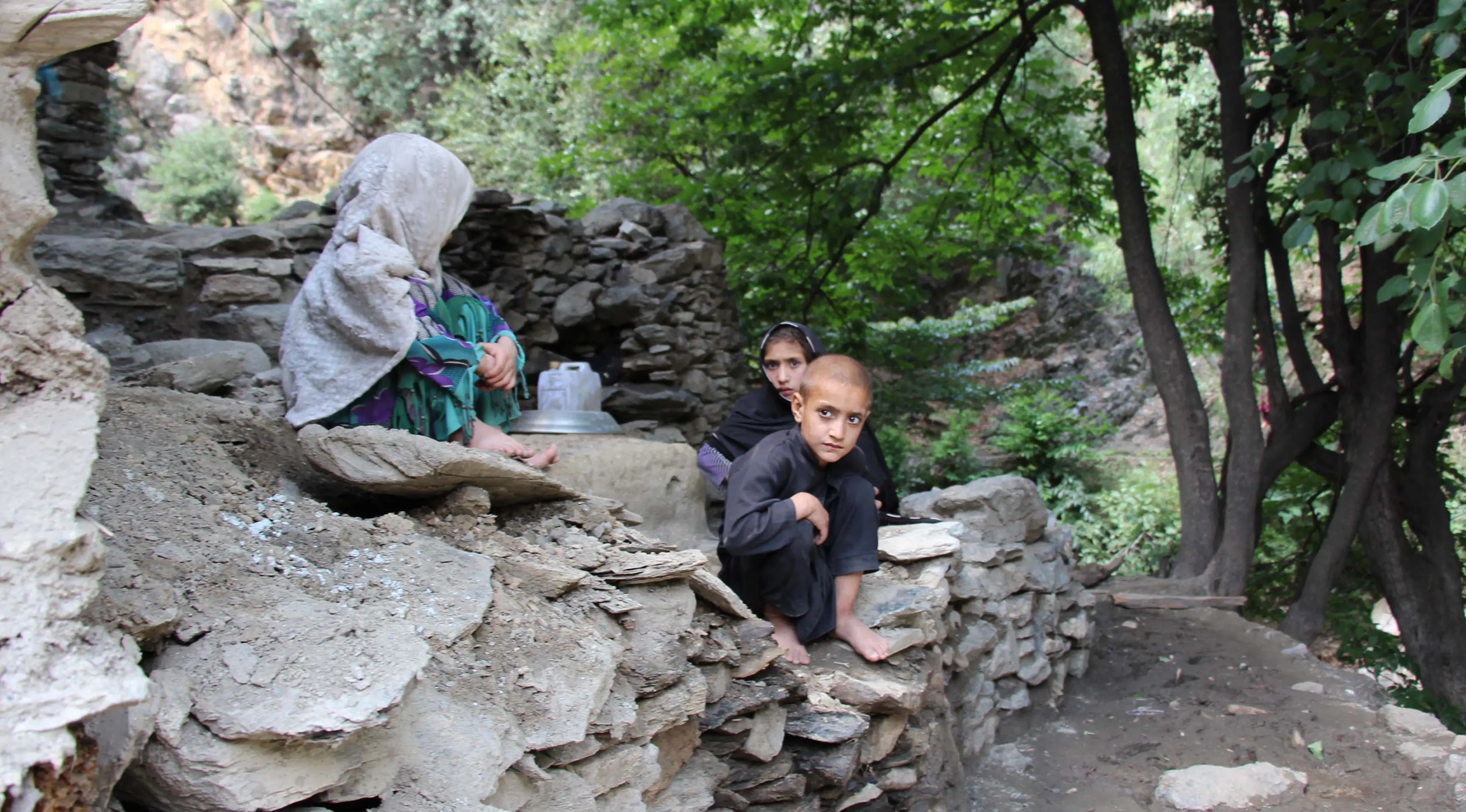 Anak-anak duduk di atas bebatuan setelah banjir bandang menghantam wilayah Ursoon, daerah terpencil Chitral di Pakistan utara, Minggu (3/7). Banjir bandang akibat hujan lebat yang lama itu telah menewaskan sedikitnya 43 orang. (GUL HAMAAD Farooqi/AFP)