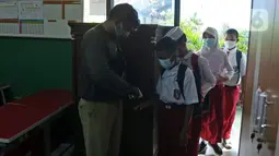 Para murid SDN Kota Baru menjalani pemeriksaan suhu tubuh saat akan mengikuti ujian penilaian akhir sekolah di SDN Kota Baru 3 Bekasi, Jawa Barat, Senin (8/6/2021). Ujian dibagi dua sesi, jam 7.00 WIB - 9.00 WIB dan 9.30 - 11.00 WIB. (Liputan6.com/Herman Zakharia)