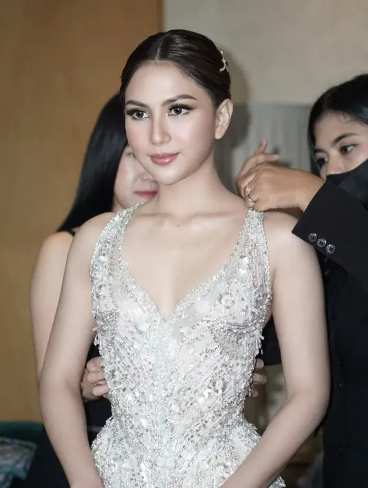 Gaun ini memiliki garis leher yang dalam, high-slit, dan backless yang dihiasi dengan aksesori berbentuk pita yang menyilang.