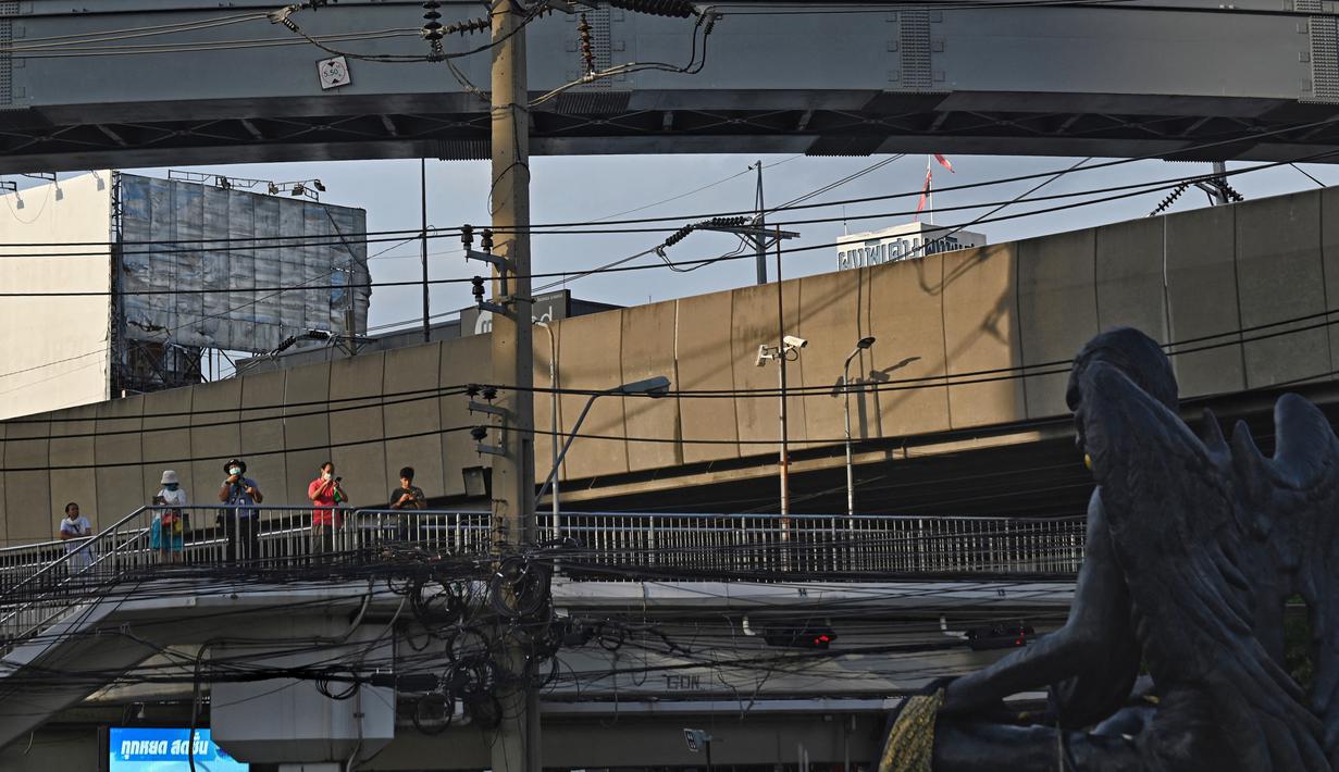 Sebuah patung hitam besar yang kurus dan bersayap dengan taring emas dan cakar merah menatap ke bawah di jalan Bangkok yang sibuk, kemunculannya yang tiba-tiba memicu kekhawatiran dan seruan untuk memindahkannya. (Lillian SUWANRUMPHA / AFP)