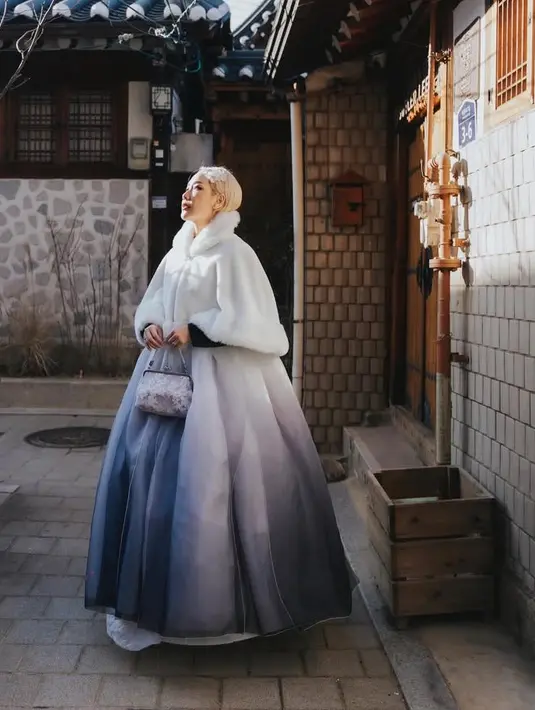 Bunga Citra Lestari mengenakan hanbok warna ungu salur putih terlihat pada bagian rok yang mengembang. Hanbok pun dilengkapi luaran model crop putih dengan aksen bulu pada bagian leher dan bawah.  [@itsmebcl]