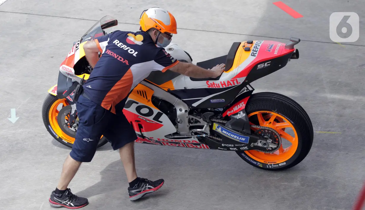 Teknisi Repsol Honda Team mendorong motor tunggangan Marc Marquez saat sesi Warm Up MotoGP di Pertamina Mandalika International Street Sirkuit, Nusa Tenggara Barat, Minggu (20/3/2022). (Liputan6.com/Helmi Fithriansyah)