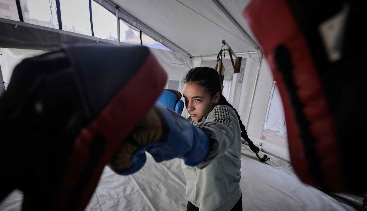 Rahaf Abu Hasira, 14 tahun, saat berlatih di klub tinju wanita yang didirikan di dalam tenda di Kota Gaza, Selasa 5 Mei 2026. (AP Photo/Jehad Alshrafi)