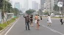Warga memanfaatkan kondisi lengang sebagian ruas jalan Jenderal Sudirman untuk berfoto, Jakarta, Minggu (27/10/2019). Sebagian ruas Jalan Jenderal Sudirman dialihkan akibat  berlangsungnya Karnaval Kendaraan Listrik yang bertajuk Jakarta Langit Biru. (Liputan6.com/Helmi Fithriansyah)