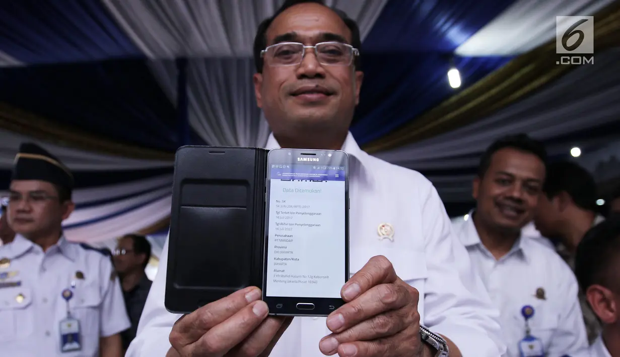 Menhub Budi Karya Sumadi menunjukan aplikasi sistem perizinan angkutan sewa khusus berbasis daring yang diluncurkan di Jakarta (16/7).(Liputan6.com/Herman Zakharia)