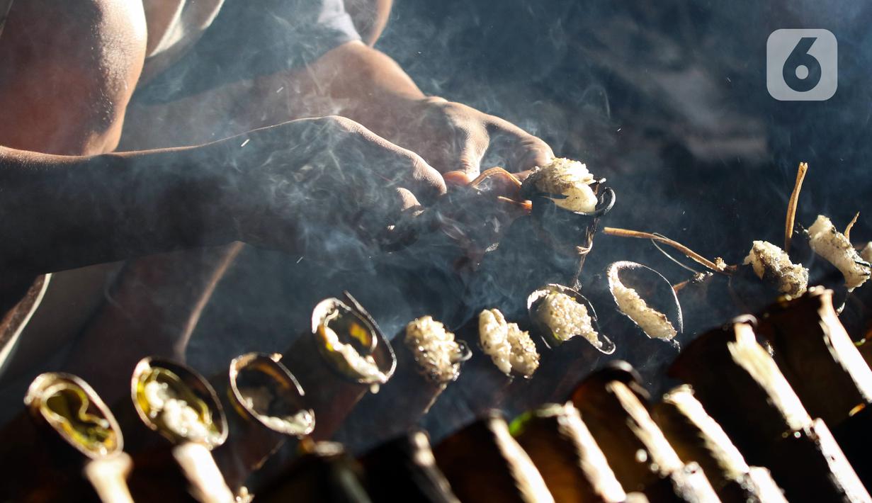 Pekerja melakukan pembakaran lemang bambu di Jalan Kramat Raya, Senen, Jakarta Pusat, Rabu (6/4/2022). Selama Ramadhan, pembuat lemang mampu memproduksi hingga 300 buah dalam sehari, meningkat hingga tiga kali lipat dari hari biasa. (Liputan6.com/Herman Zakharia)