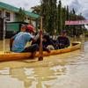 Warga menggunakan perahu untuk melewati jalan yang tergenang banjir setelah hujan lebat dan tanggul jebol, di Lhoksukon, Aceh Utara, 7 Oktober 2022. (AFP/Azwar Ipank)