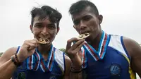 Pedayung Jawa Barat, Muhamad Yunus dan Syarifudin, menggigit medali emas PON XIX 2016 usai memenangi nomor 1.000 meter Kano 2 di Situ Cipule, Karawang, Jawa Barat, Senin (19/9/2016). (Bola.com/Vitalis Yogi Trisna)