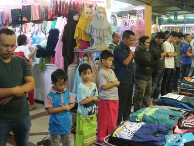 Sejumlah umat muslim melaksanakan salat jumat pada bulan Ramadan di antara pakaian yang dijajakan di kios Pasar Tanah Abang, Jakarta, Jumat (25/5). Jemaah terpaksa melakukan salat di lorong kios karena terbatasnya ruang masjid (Liputan6.com/Arya Manggala)
