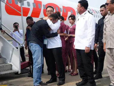 Menteri Luar Negeri Indonesia Sugiono (tengah) memeluk seorang Warga Negara Indonesia (WNI) yang pernah bekerja di pusat penipuan di Myanmar, dengan disaksikan oleh Menteri Koordinator Bidang Politik, Hukum, dan Keamanan Budi Gunawan (kedua dari kanan), di Bandara Internasional Soekarno-Hatta, Tangerang, Banten, pada Selasa 18 Maret 2025. (Tatan SYUFLANA/POOL/AFP)
