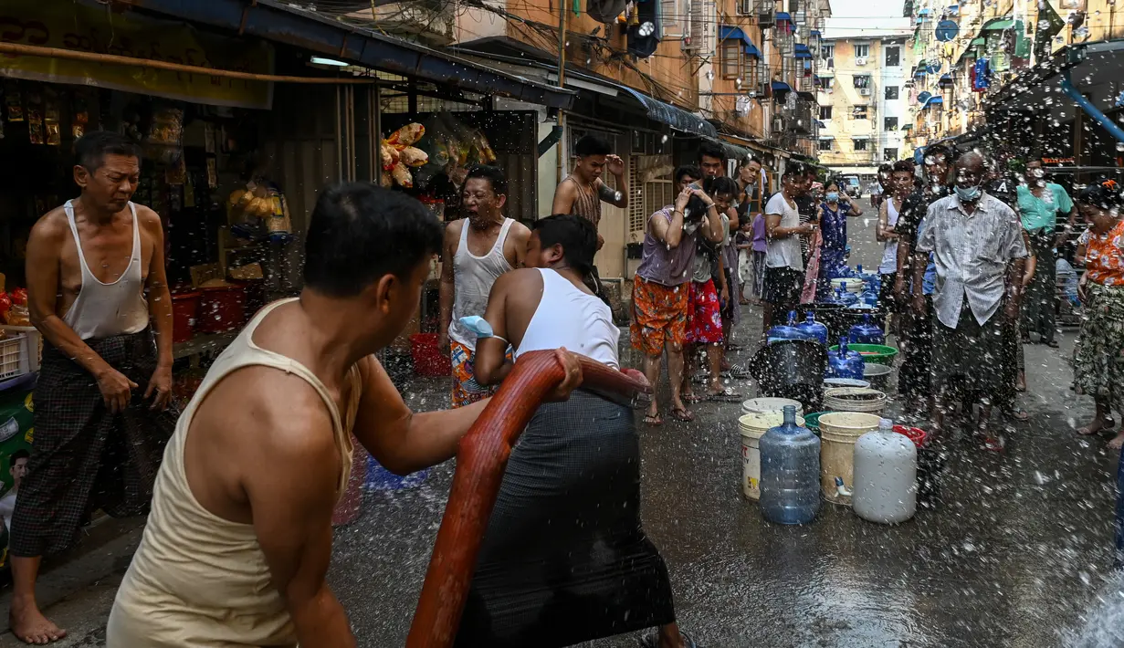 Orang-orang bereaksi saat memegang semprotan air saat mengisi wadah di Yangon, Myanmar (14/3/2022). Ribuan orang menghadapi kekurangan air karena pemadaman listrik di kota tersebut. (AFP/STR)