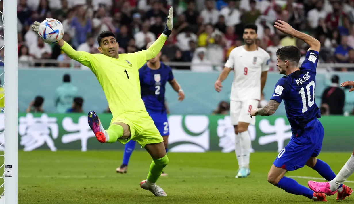 Gelandang Amerika Serikat Christian Pulisic (kanan) menembak untuk mencetak gol pertama timnya melewati kiper Iran Alireza Beiranvand pada laga pamungkas Grup B Piala Dunia 2022 di Stadion Al Thumama, Rabu (30/11/2022) dini hari WIB. Gol tunggal kemenangan AS dicetak oleh Christian Pulisic di menit ke-38. (AP Photo/Manu Fernandez)