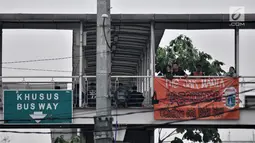 Suporter Persija (The Jakmania) berdiri di dekat spanduk dukungan Persija yang terpasang di Jembatan Penyeberangan Orang (JPO), Jakarta, Minggu (9/12). (Merdeka.com/Iqbal S. Nugroho)